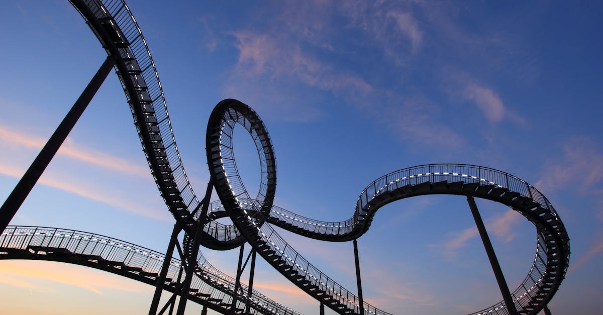 An intricate roller coaster silhouette with loops and curves set against a vibrant sunset sky.