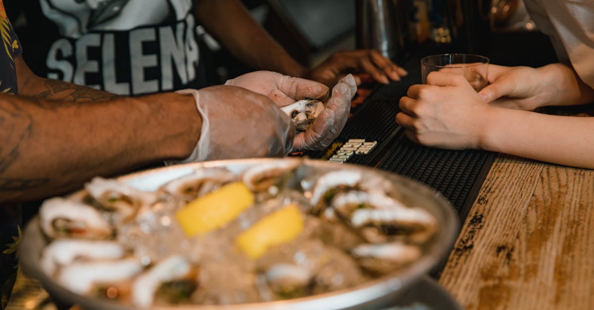 Close-up of fresh oysters being prepared at a bar counter with lemons on ice.