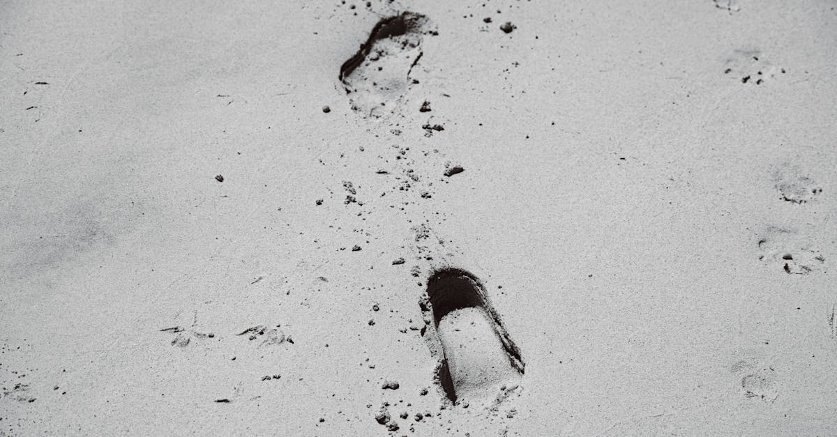 Black and white image of footprints in the sand, showcasing solitude and journey.