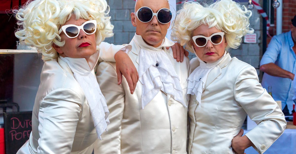 An eccentric trio in white costumes and oversized sunglasses pose playfully. Vibrant street scene.