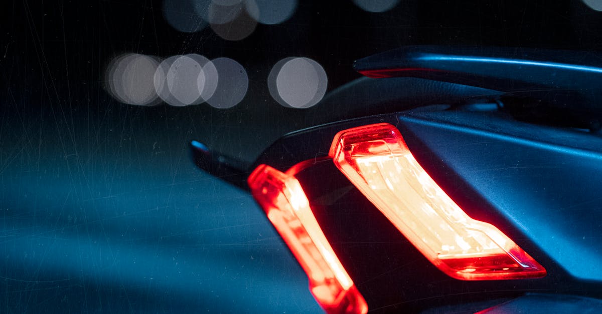 A detailed view of a motorcycle taillight glowing brightly against the dark night, showcasing vibrant bokeh.