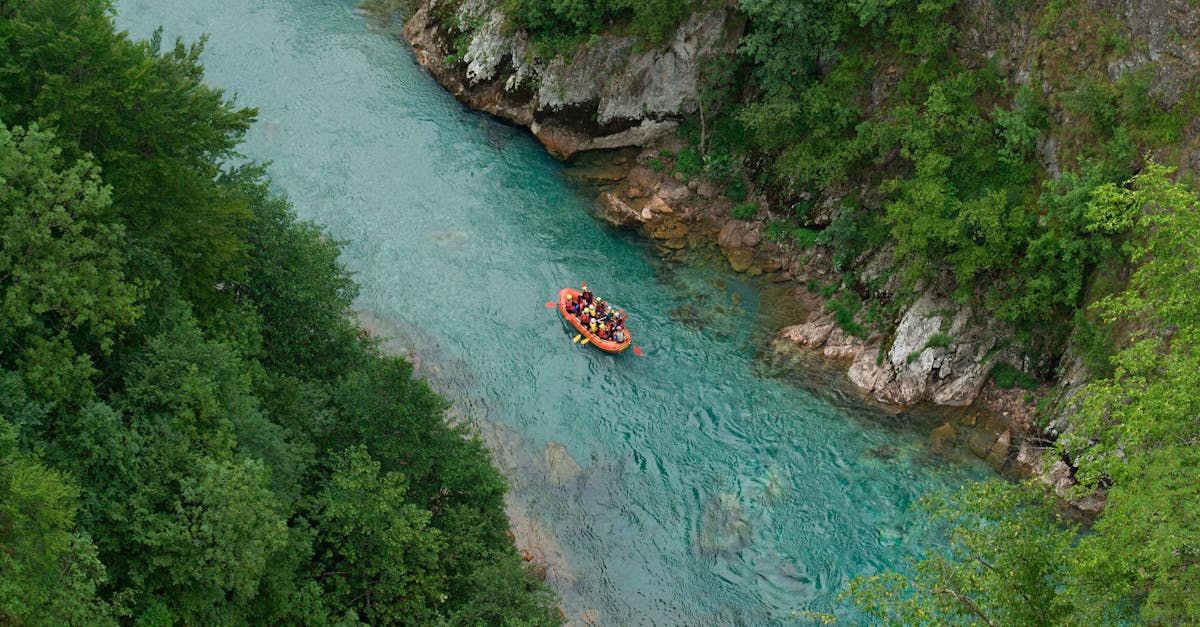 Aerial view of a group rafting down a vibrant turquoise river in Montenegro, surrounded by lush greenery.