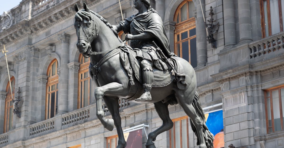 Equestrian statue of Charles IV in front of historic building in Mexico City.