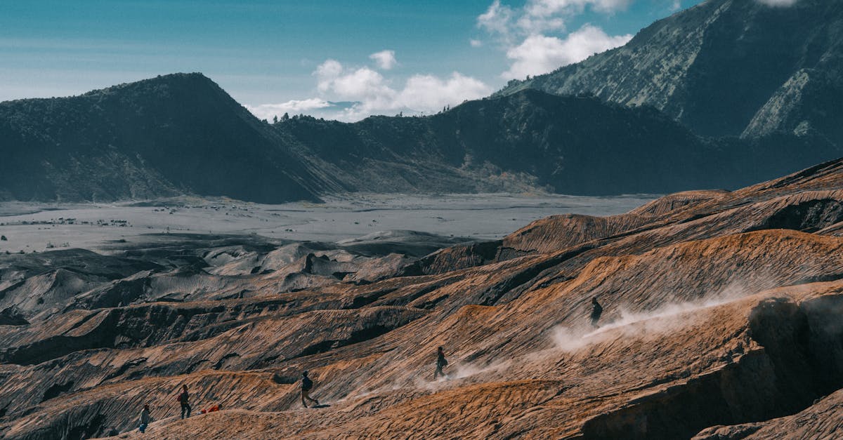 Hikers trekking on rugged volcanic terrain with stunning mountain views.