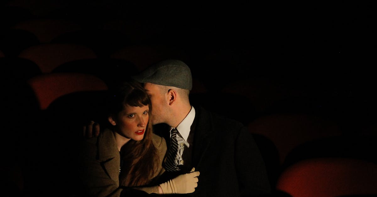 A couple in love whispers in a dimly lit cinema, evoking a sense of intimacy and vintage allure.