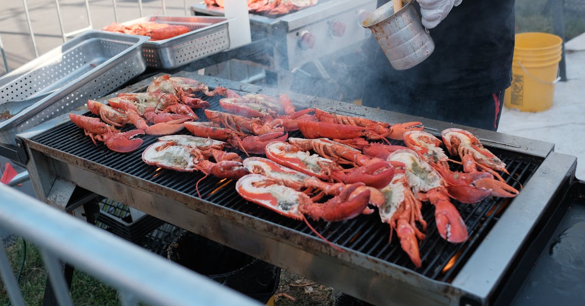 Fresh lobsters being grilled outdoors on a barbecue with seasoning for a flavorful meal.