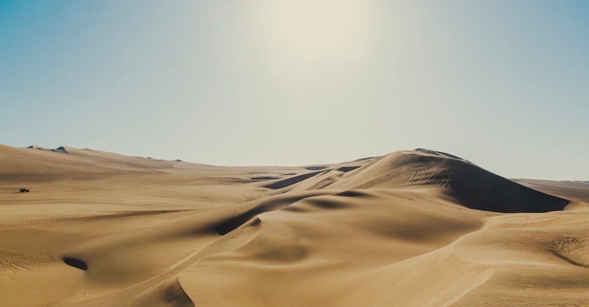 Golden sand dunes stretch under a clear sky in Ica, Peru, showcasing nature's arid beauty.