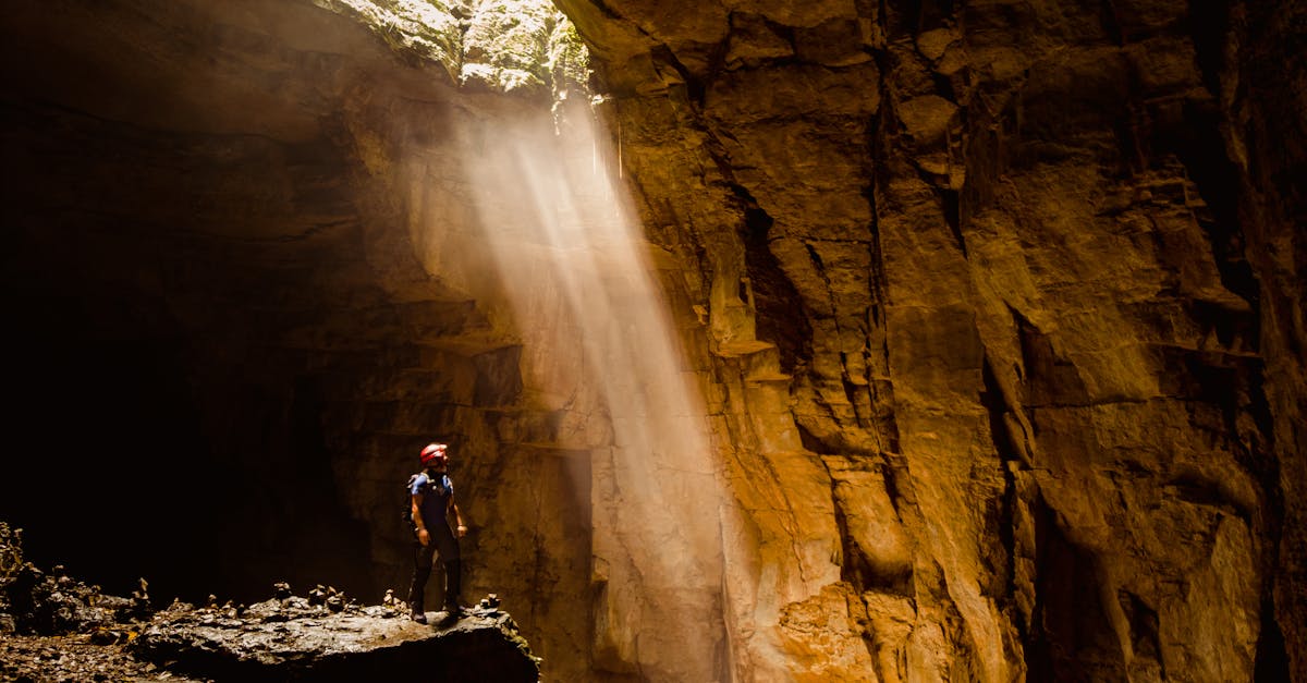 A lone explorer stands beneath a sunbeam in a majestic cave in Cuetzalan, Mexico, inspiring awe and adventure.