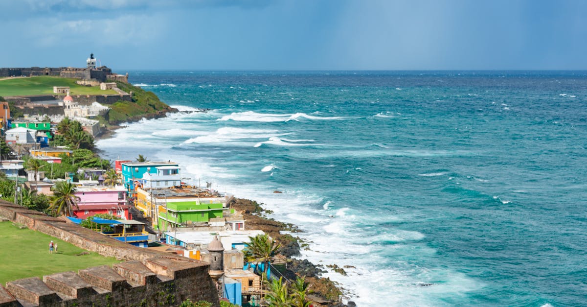 Colorful town along San Juan's coastline with waves crashing against the shore under a moody sky.