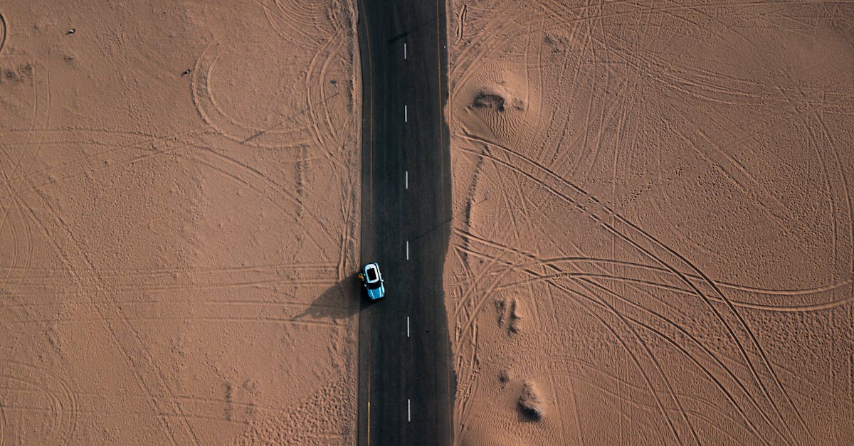 Drone view of a car driving through a desert road in Dubai, UAE.