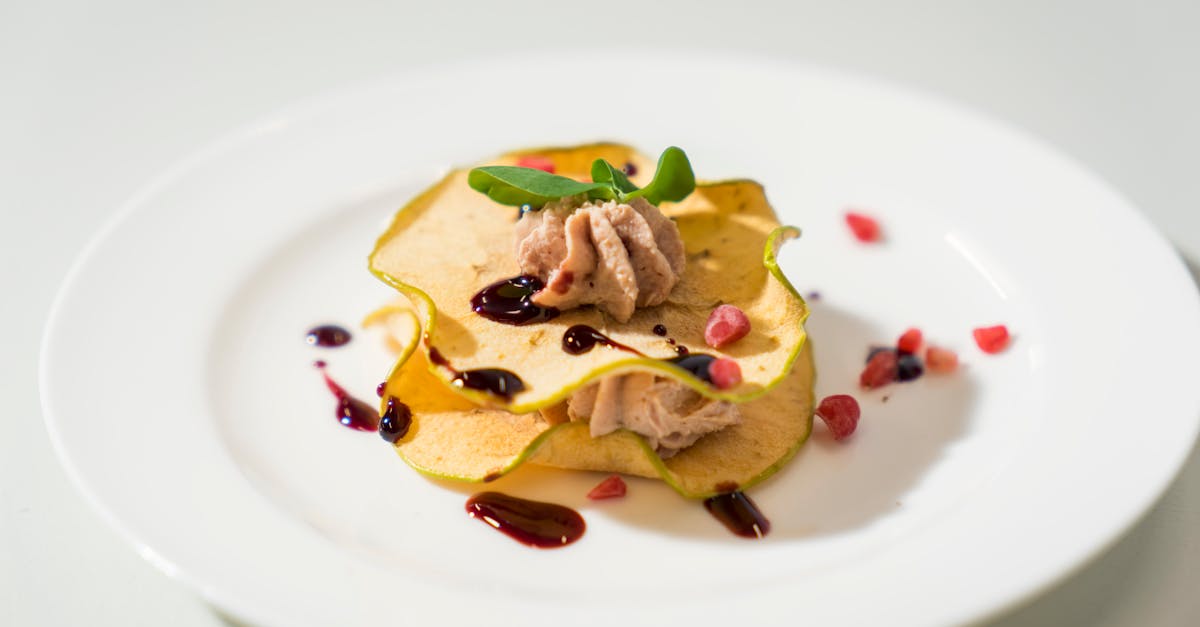 A stylishly presented dessert on a white plate, adorned with fresh garnishes and a drizzle of sauce.