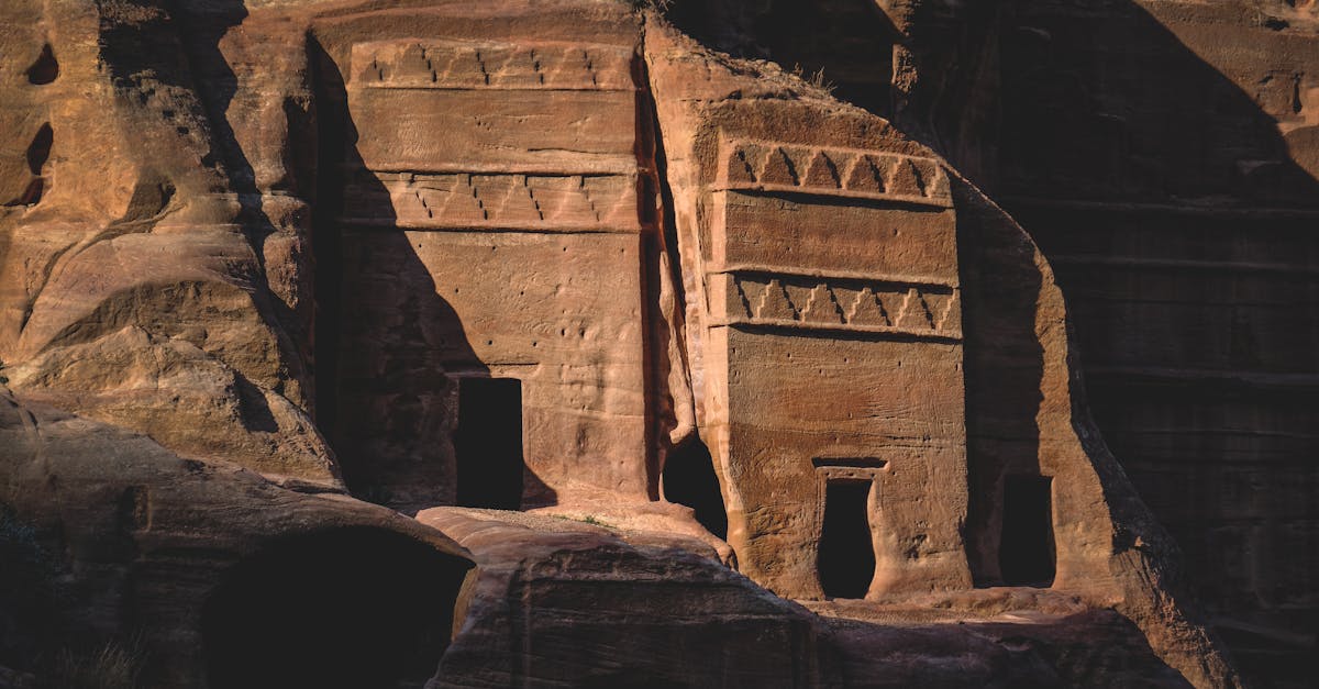 Detailed view of sunlit ancient rock carvings on a stone cliff, showcasing historical architectural artistry.