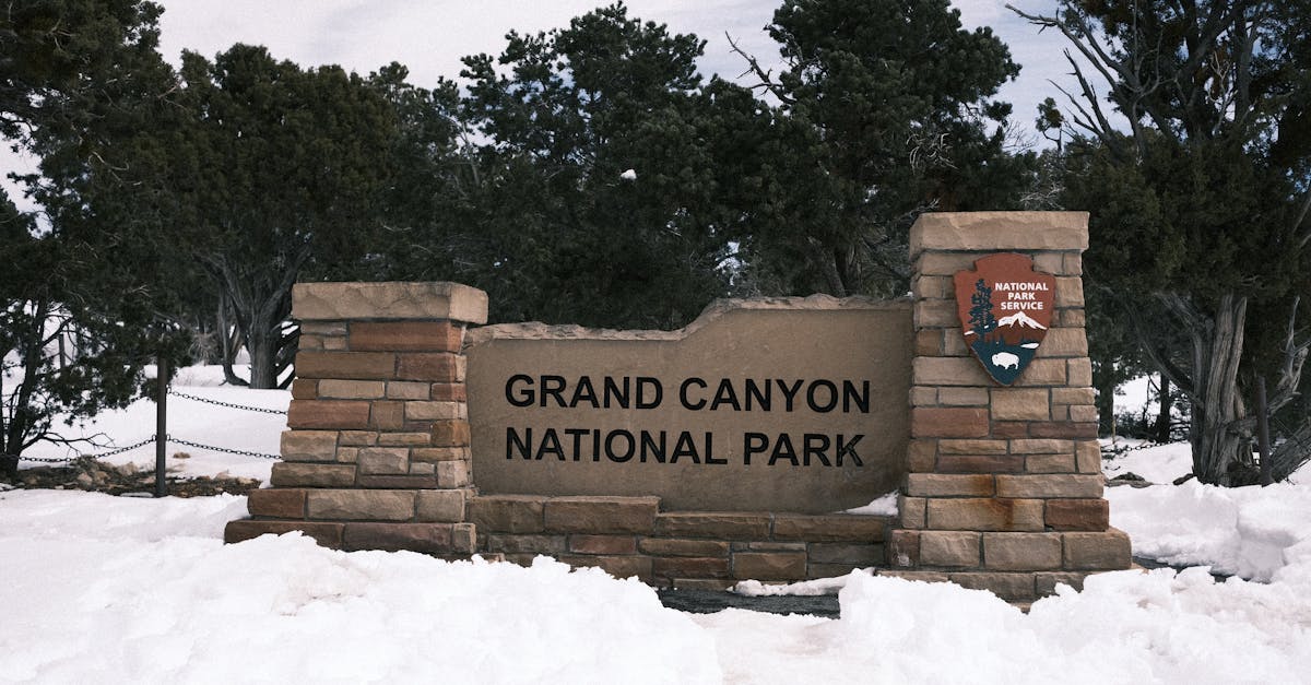 Snow-covered entrance sign to Grand Canyon National Park in winter.