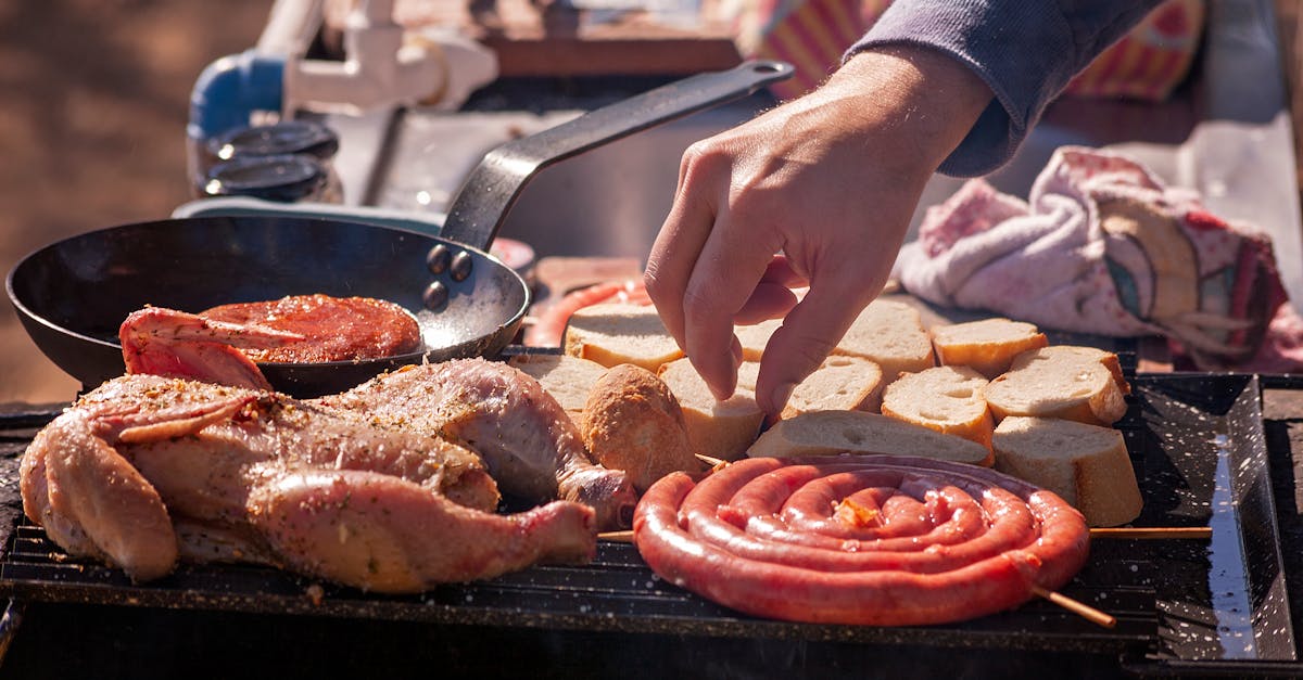 Close-up of a hand grilling meats and bread at an outdoor barbecue. Perfect for food and lifestyle themes.
