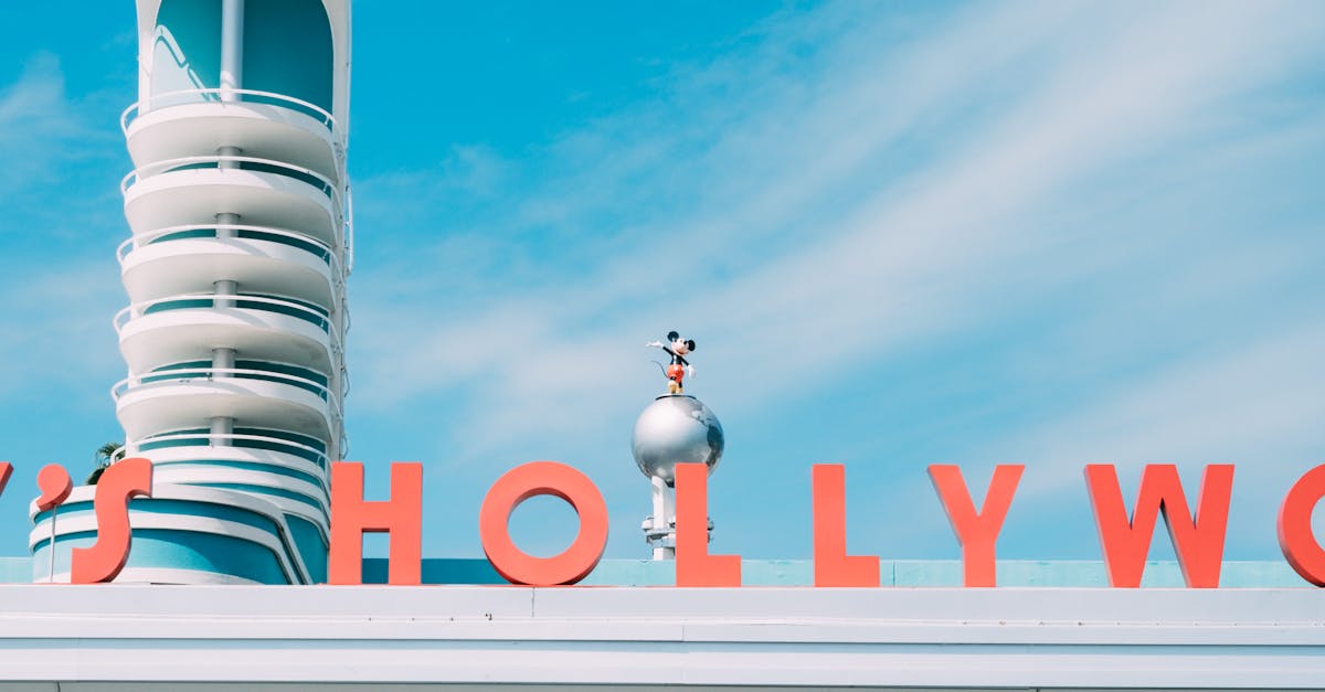 Vibrant photo of Disney's Hollywood Studios sign featuring a Mickey Mouse statue against a clear blue sky.