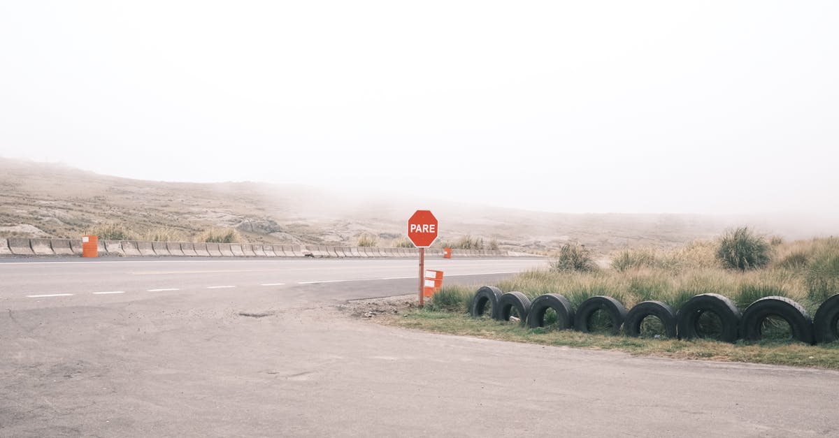 Empty foggy road with a stop sign and tires, creating a moody summer scene.