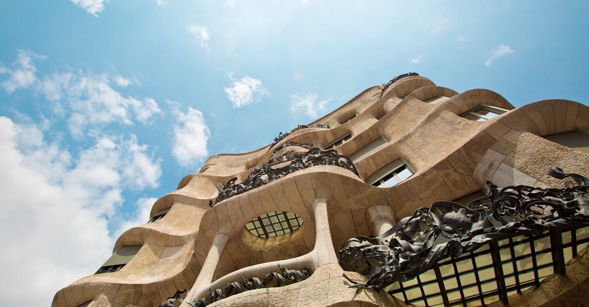 Low angle view of the Casa Milà's unique architectural facade against a vibrant sky.