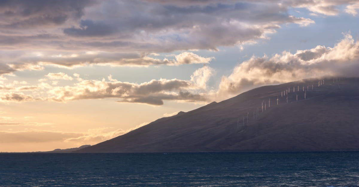 Serene sunset view over Kihei, Hawaii with wind turbines along the coast, capturing nature and renewable energy.