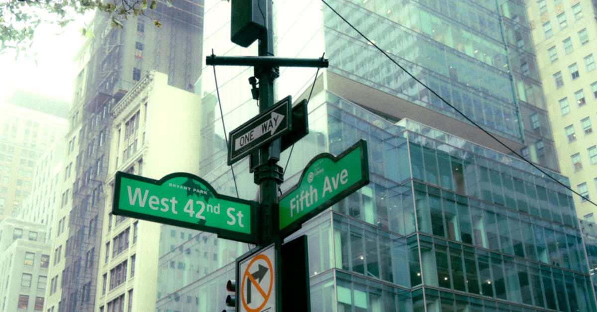 Street signs at the corner of West 42nd Street and Fifth Avenue in NYC, showcasing urban architecture.