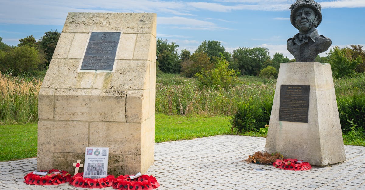 A World War II memorial featuring a stone monument and a bust, surrounded by wreaths in a serene park setting.