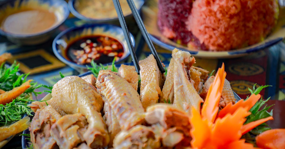 Close-up of a traditional Asian chicken dish with chopsticks, colorful rice, and vegetables.