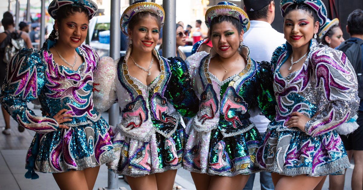 Four women in colorful, sequined costumes pose in a vibrant street parade in New York City.