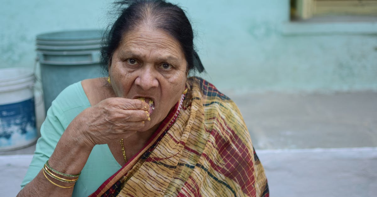 Senior woman in a sari eats traditional meal outdoors in Hyderabad, India.