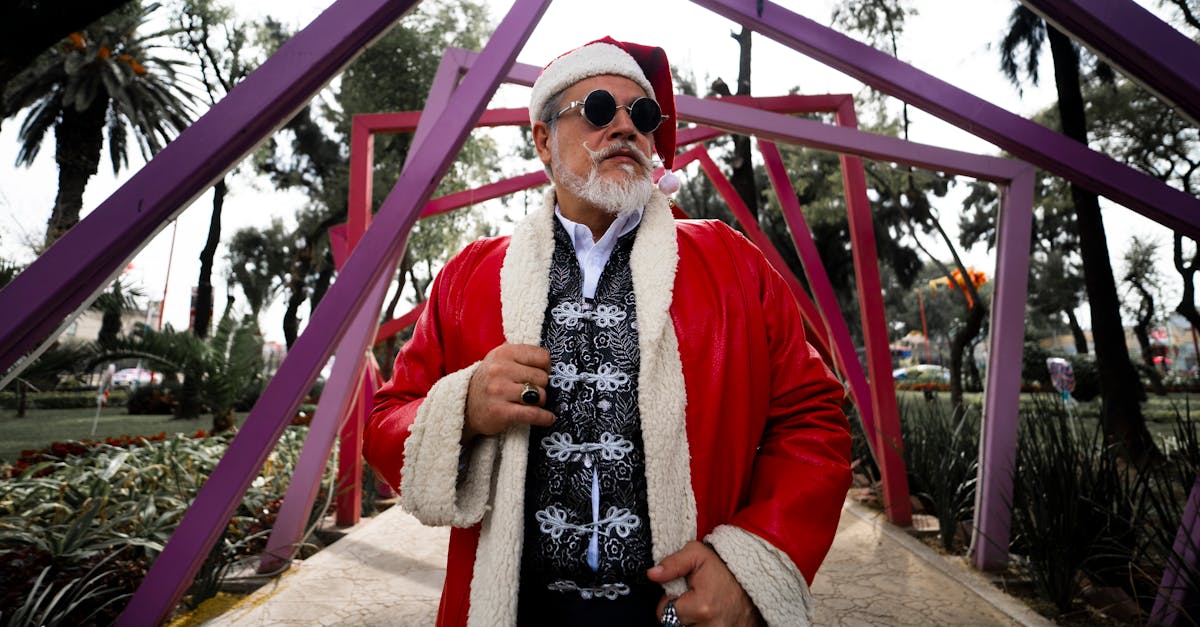 Outdoor portrait of a fashionable Santa Claus with sunglasses and red coat in a vibrant setting.