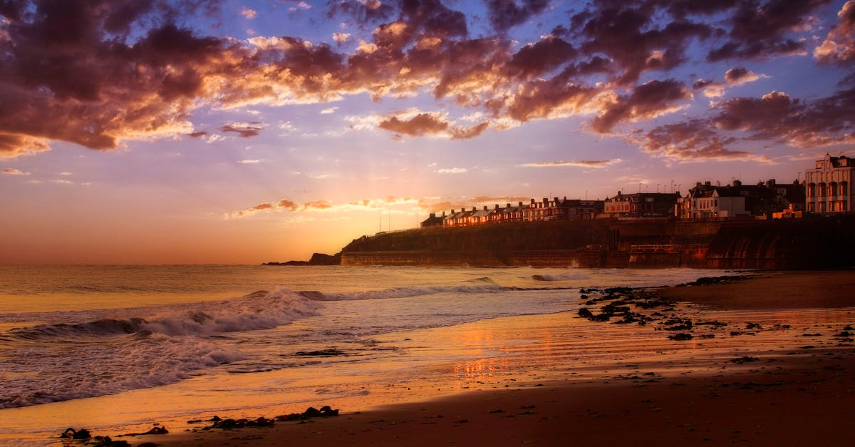 Stunning sunset over a coastal urban area with dramatic clouds and reflections.