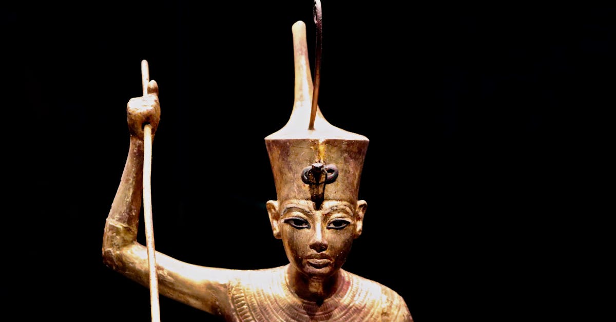 Close-up of an ancient Egyptian pharaoh gold statue on a black background.