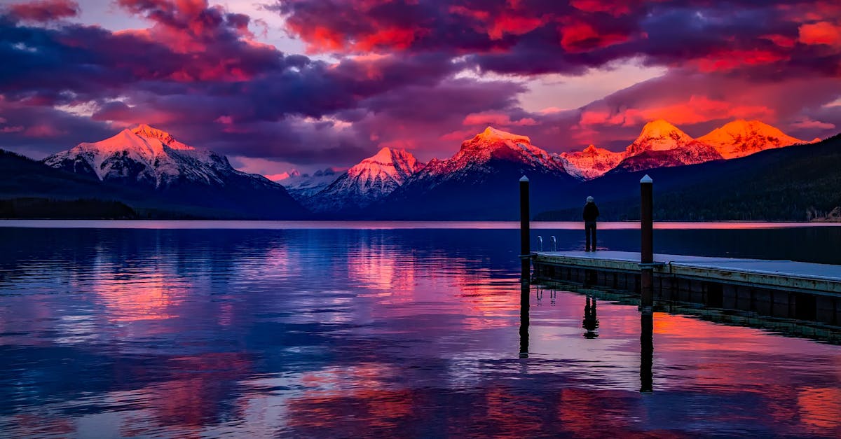 Stunning sunset over a serene lake with colorful sky and majestic mountains.