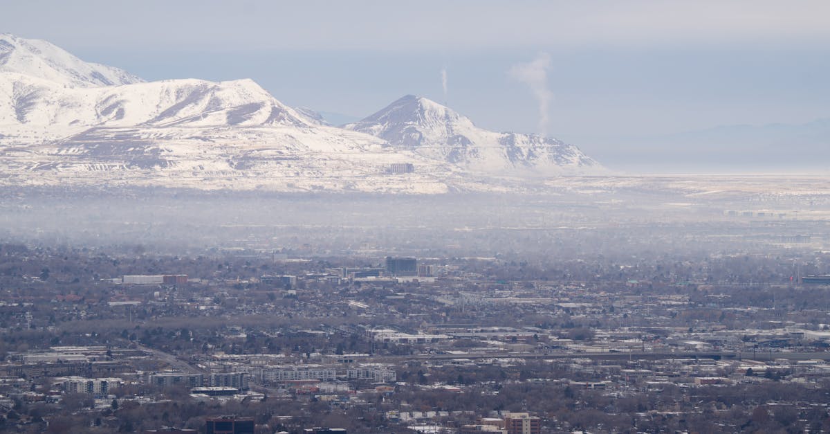 Aerial view of Salt Lake City with snow-capped mountains in the background under a hazy sky.