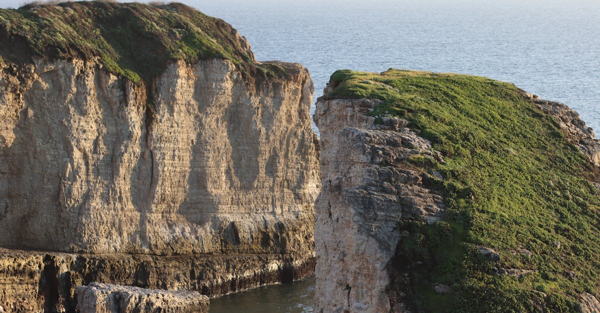 Scenic view of rocky cliffs with greenery against a tranquil sea backdrop.