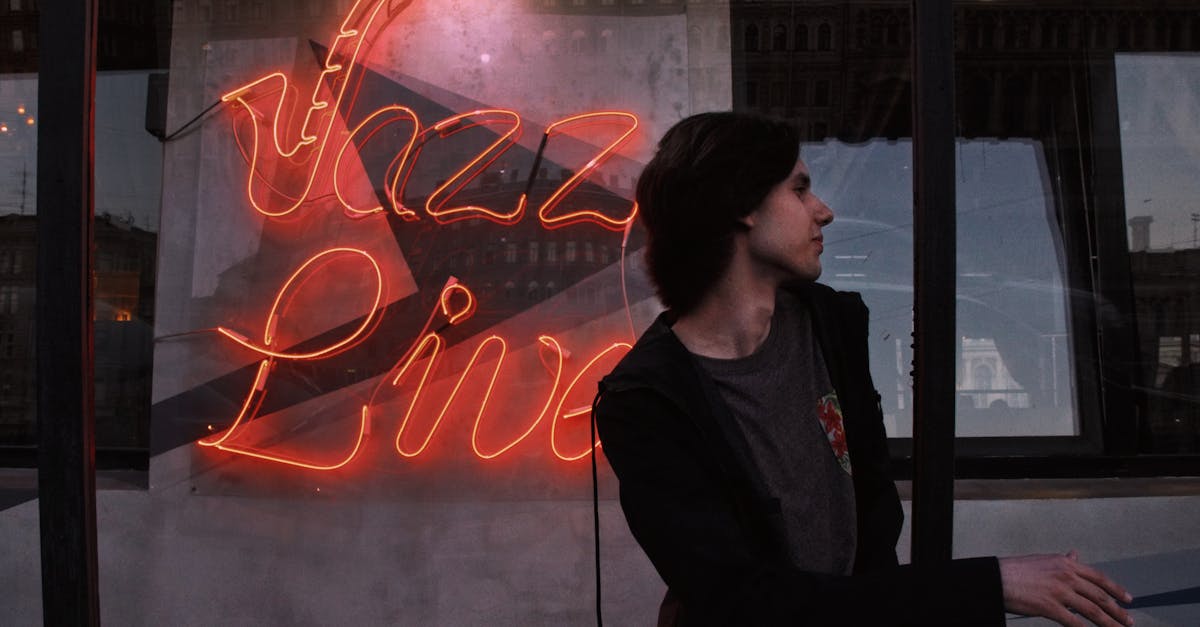 A neon 'Jazz Live' sign lights up the night with a young man standing beside it, creating a cool, urban vibe.