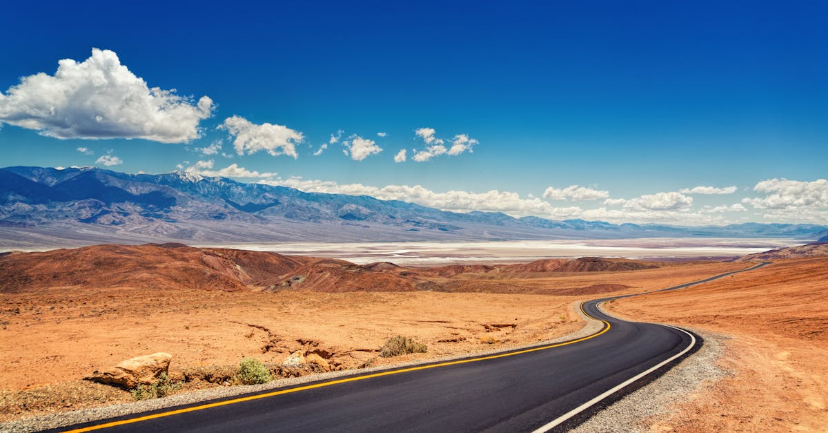 A winding highway through the vast desert with vivid blue skies and distant mountains in the backdrop.