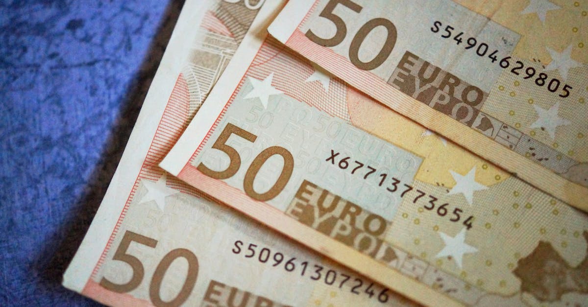 Stack of 50 Euro notes arranged on a textured surface, emphasizing European currency.
