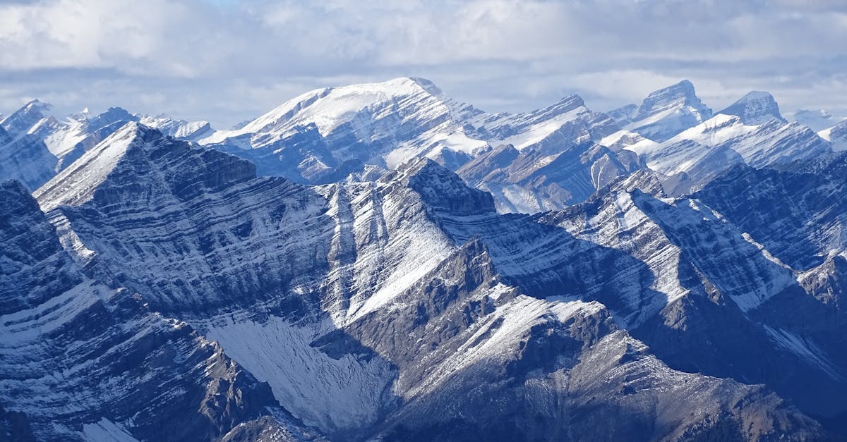 Majestic view of snow-capped Rocky Mountains under a cloudy sky in Banff National Park, Alberta.