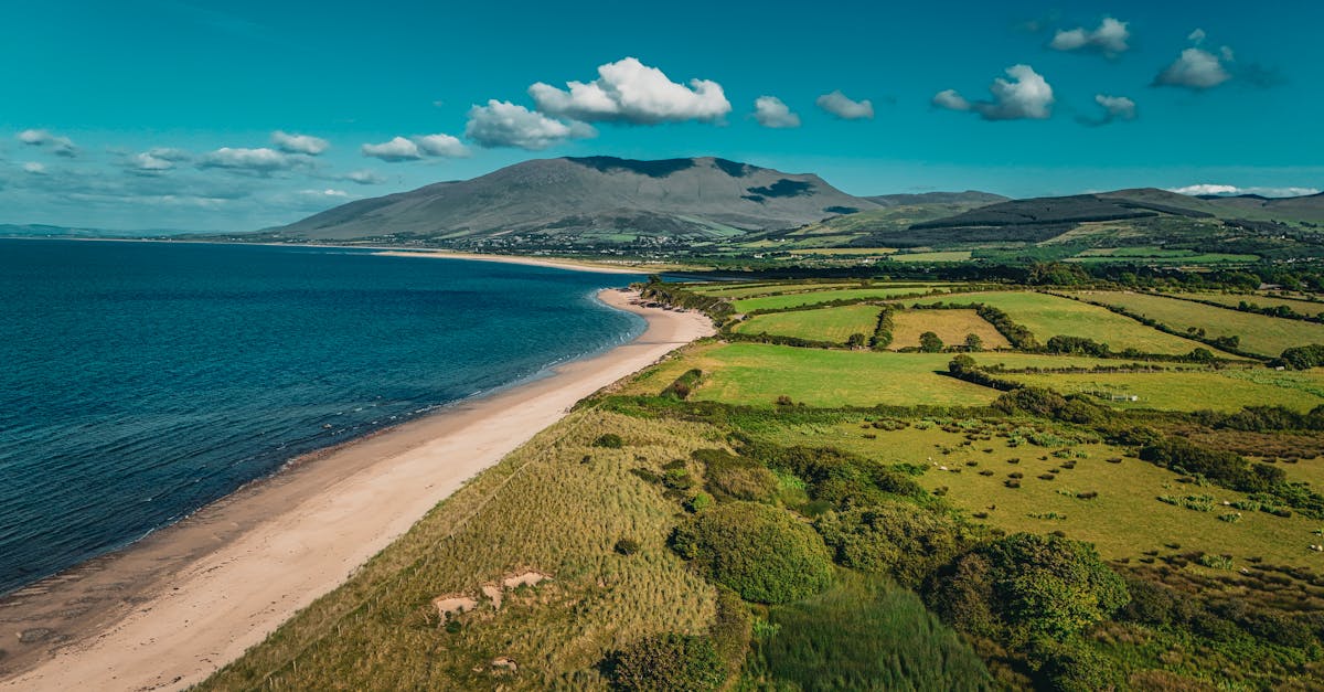 Stunning aerial view of Castlegregory Beach, Ireland, with lush greenery and blue ocean.