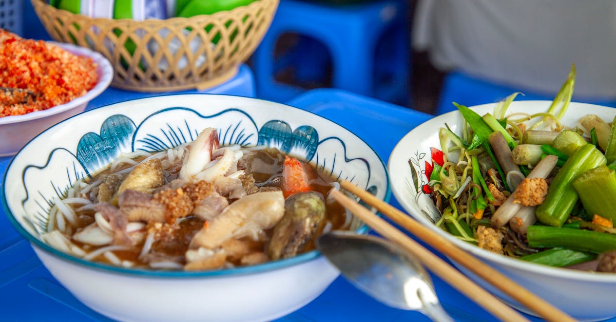 Delicious Asian noodle soup served with fresh vegetables and chopsticks on a blue table.