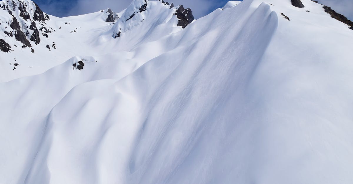 Capture the serene beauty of snow-covered mountain peaks under a clear blue sky, ideal for winter or adventure themes.