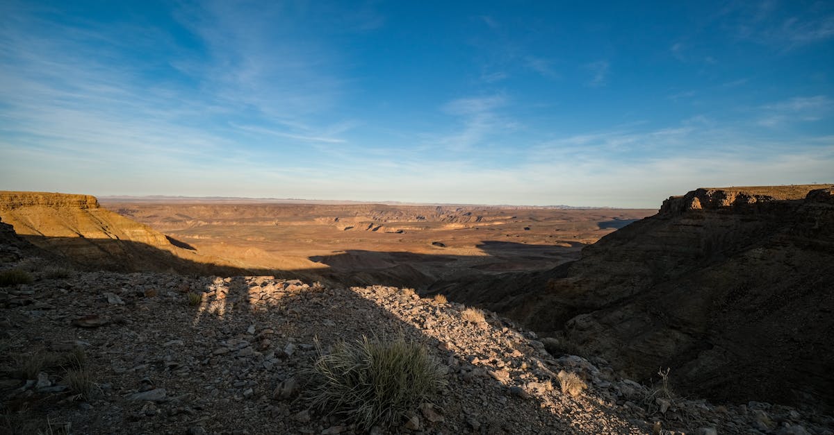 Expansive desert view with rocky terrain and clear blue skies during sunrise.