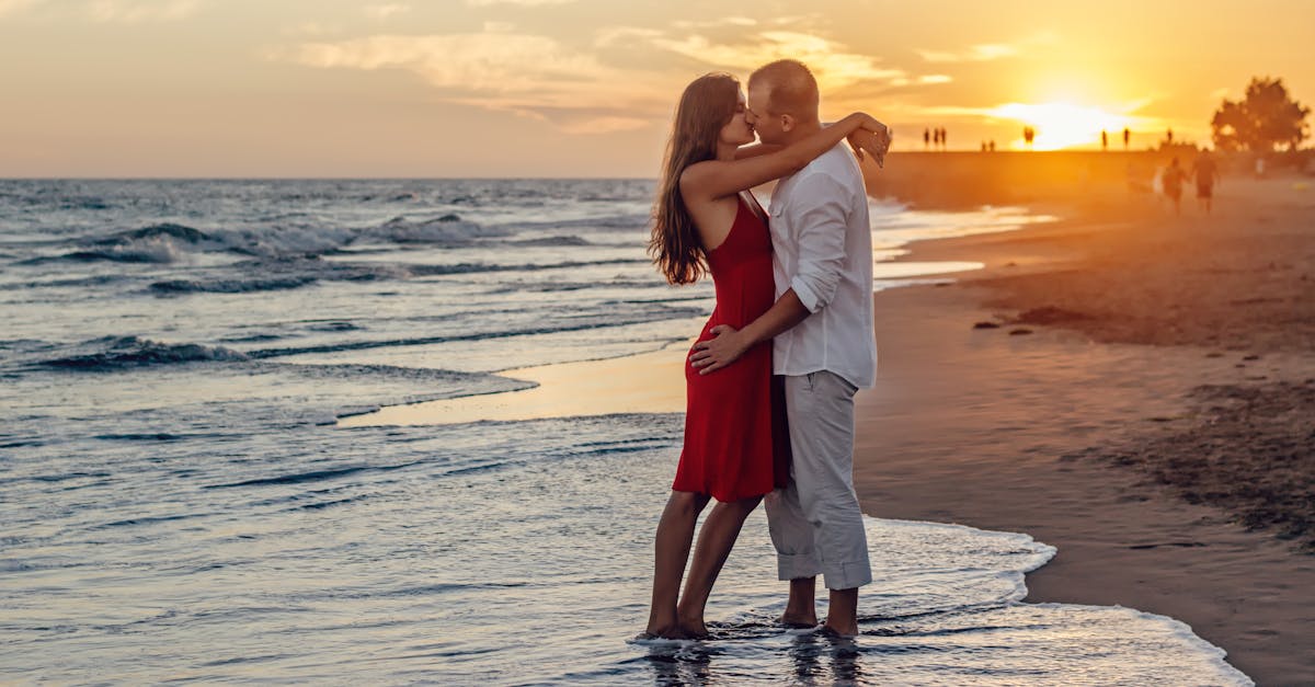 A couple in love embraces at the seaside during a vibrant sunset.