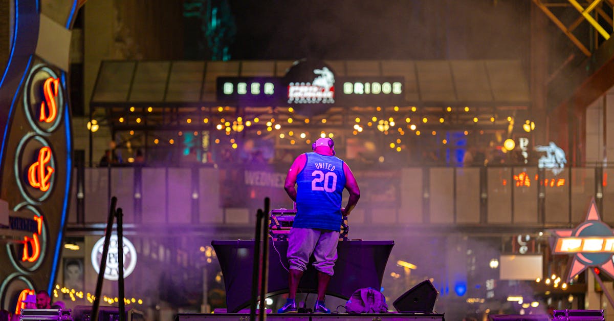 DJ performs amidst colorful lights at lively night street venue.