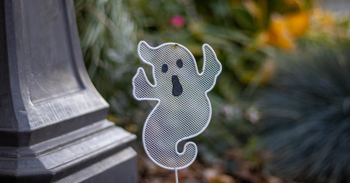 A spooky ghost decoration beside a garden post, perfect for Halloween themes.