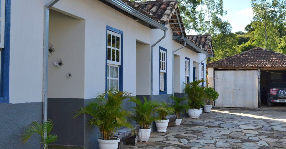 Side view of a colonial house with potted plants and blue accents.