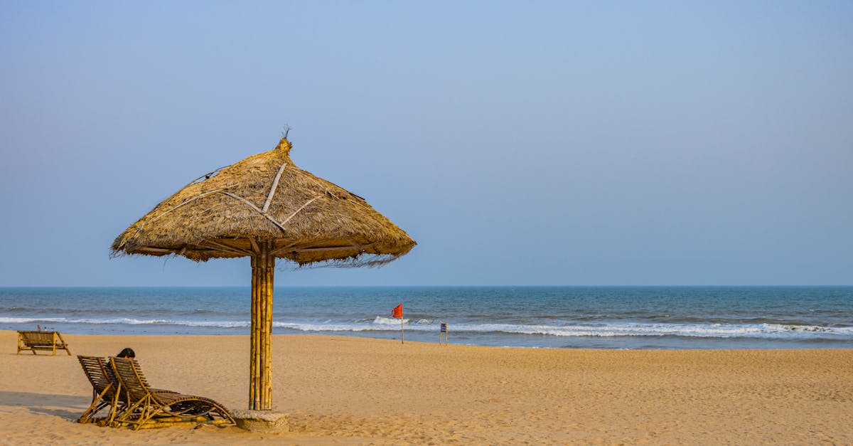 Calm beach scene in Puri, Odisha with a solitary straw umbrella by the ocean.