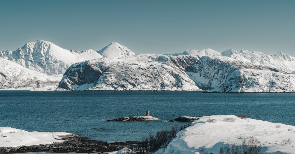 Snow-covered mountains with a serene arctic ocean view in Northern Norway.