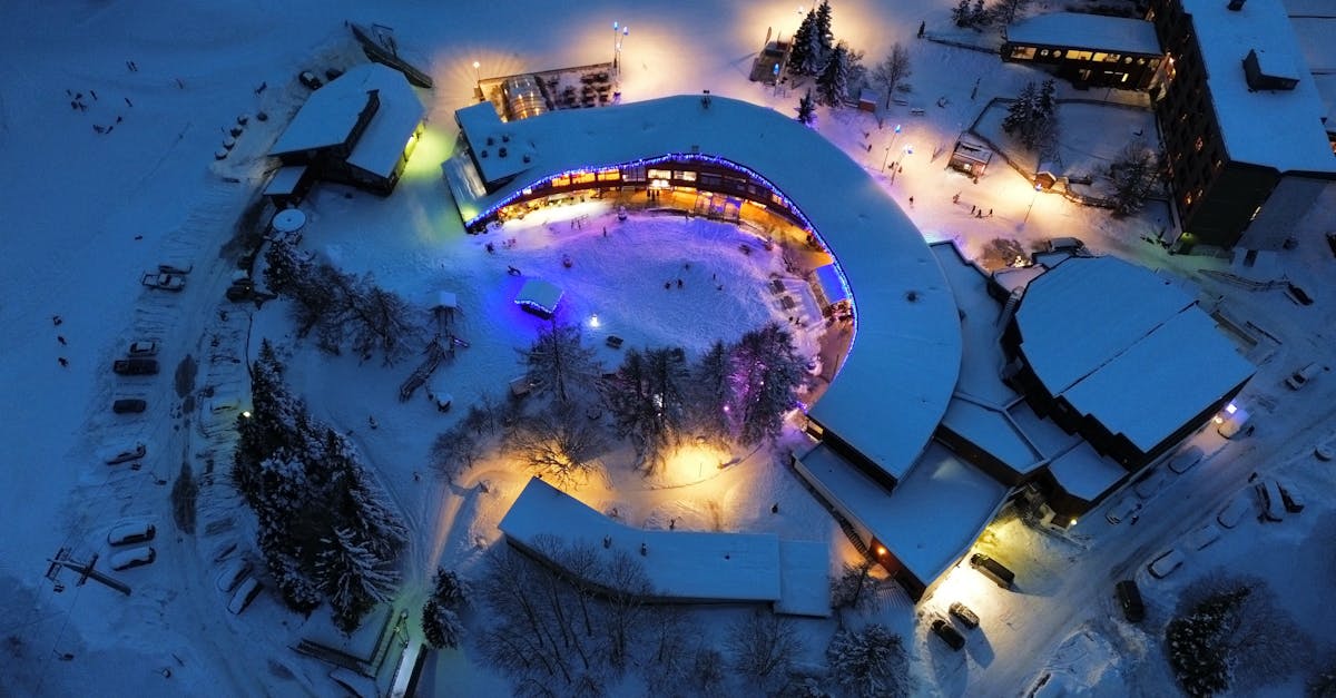Aerial view of snow-covered resort buildings at night with vibrant lights in Montricher-Albanne, France.