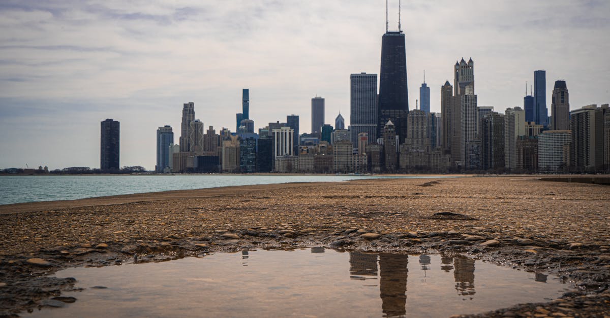 Beautiful view of the Chicago skyline with skyscraper reflections on wet ground under cloudy skies.