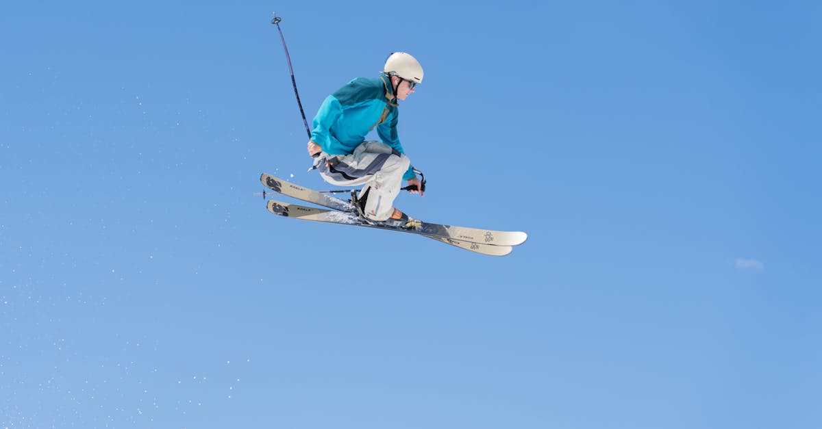 Dynamic skier jumps high in clear blue sky at Brighton Resort, Utah.
